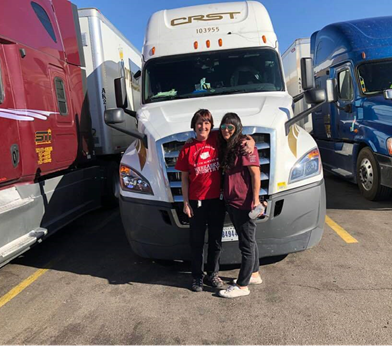 Two women in front of CRST semi truck