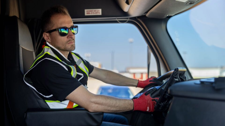 CRST truck driver wearing safety gear and sunglasses, focused on the road while driving, promoting safe driving tips for Labor Day travel.