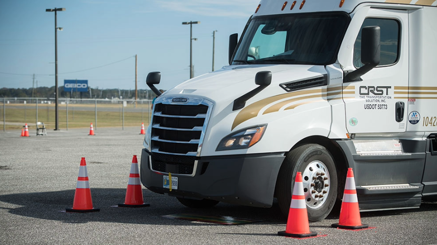 Tractor of CRST semi truck parked in parking lot with three orange safety cones