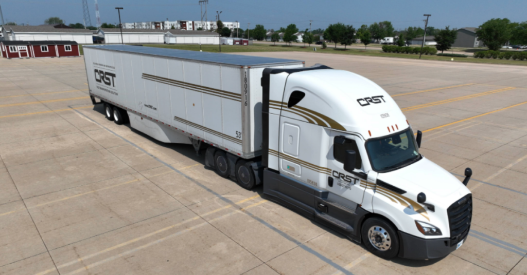 A CRST semi-truck and trailer parked in an open lot under a clear sky. The image represents best practices for avoiding overweight truck fines in freight transportation.
