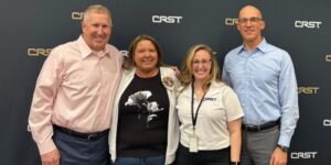 Therese Strellner: 40 years of teamwork and heart 2 Therese Strellner pictured with CRST leadership and teammates, smiling together in front of a branded backdrop during her 40th anniversary celebration.