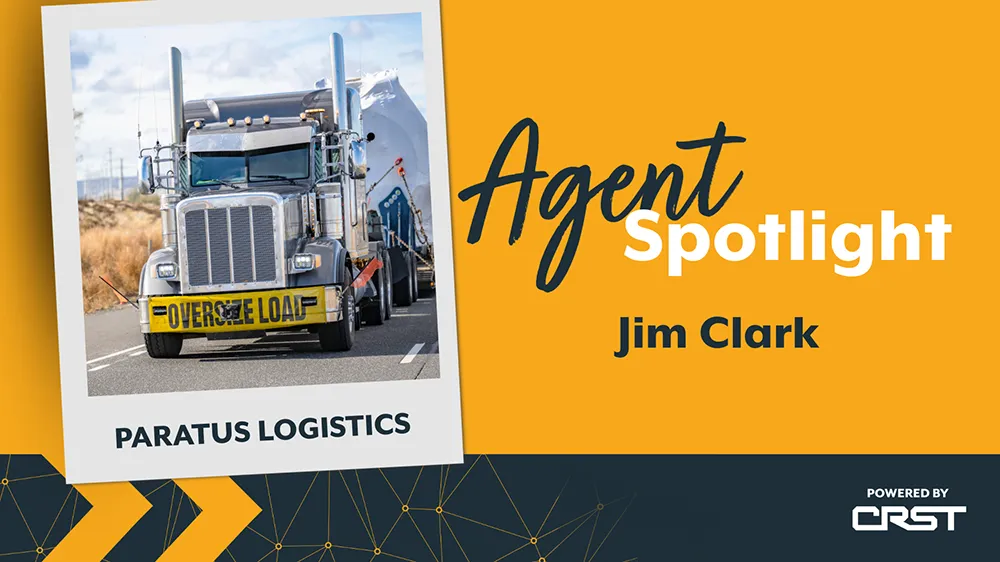 CRST agent spotlight Jim Clark. Oversized flatbed truck hauling on a highway with an “Oversize Load” sign, representing Paratus Logistics.