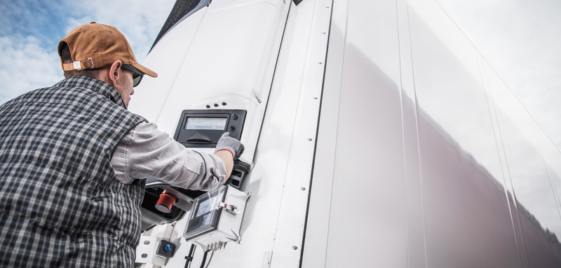 A health sciences transportation truck driver checks the temperature of his refrigerated truck