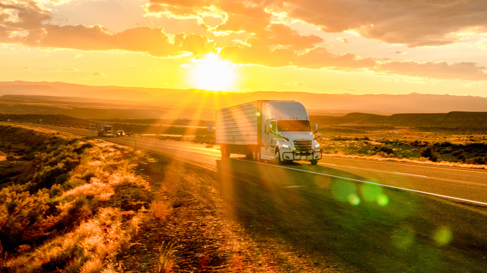 White semi-truck driving on a desert highway at sunset, reflecting the post-Montgomery trucking market